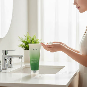 Skin TOGO Anua Heartleaf Quercetinol Moisture Cleansing foam held in hands by a woman in a bright bathroom setting.