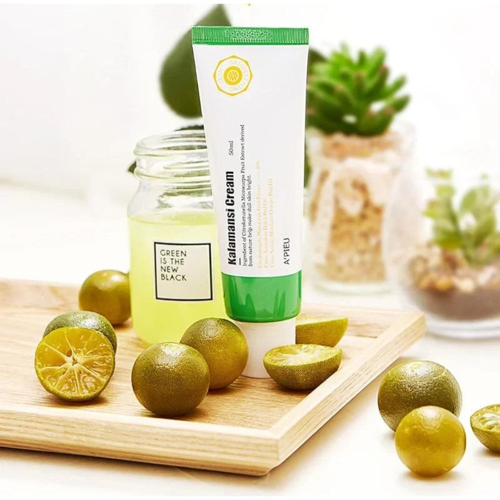 Skin TOGO A'pieu Kalamansi Cream in a white tube with green cap, displayed on a wooden tray with fresh calamansi fruit.