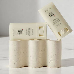 Skin TOGO Beauty of Joseon Matte Sun Stick with mugwort and camelia for SPF 50+ protection on a textured stone stand.