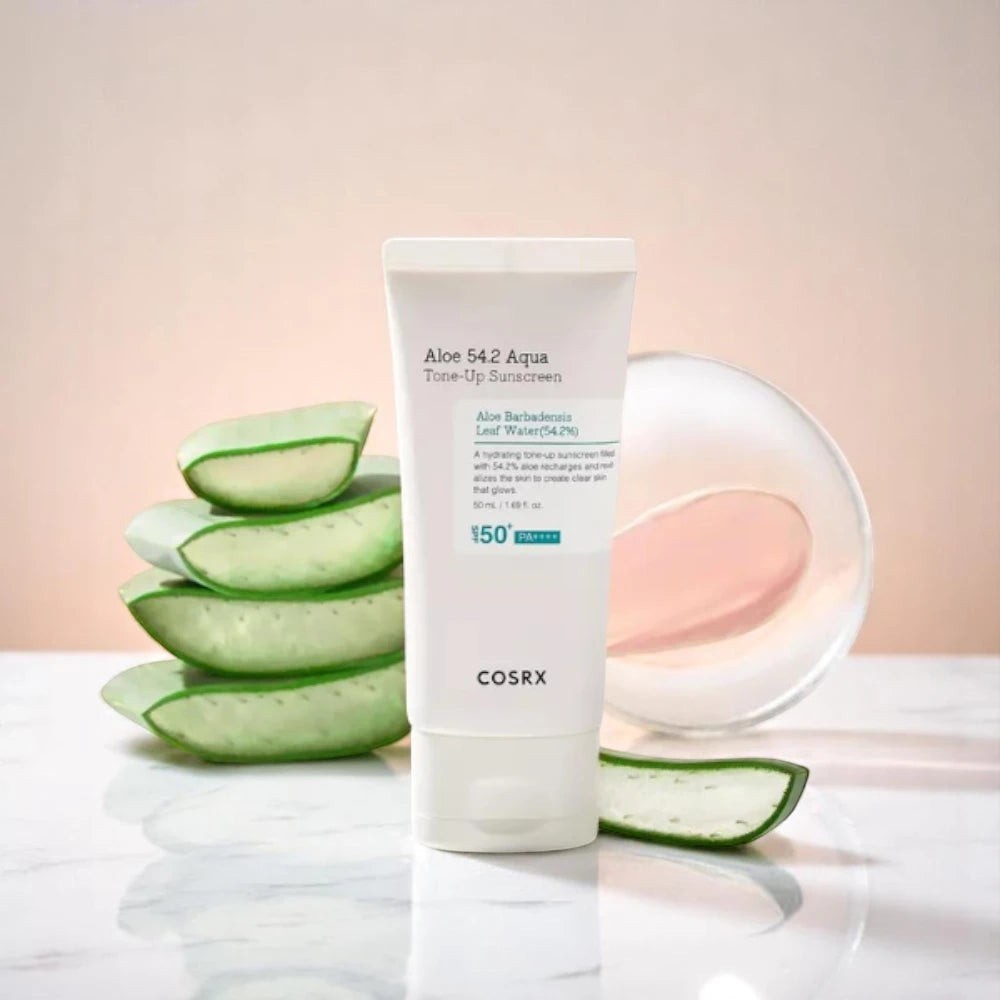 Skin TOGO COSRX Aloe 54.2 Aqua Tone-Up Sunscreen in a white tube with fresh aloe vera slices on a marble surface.