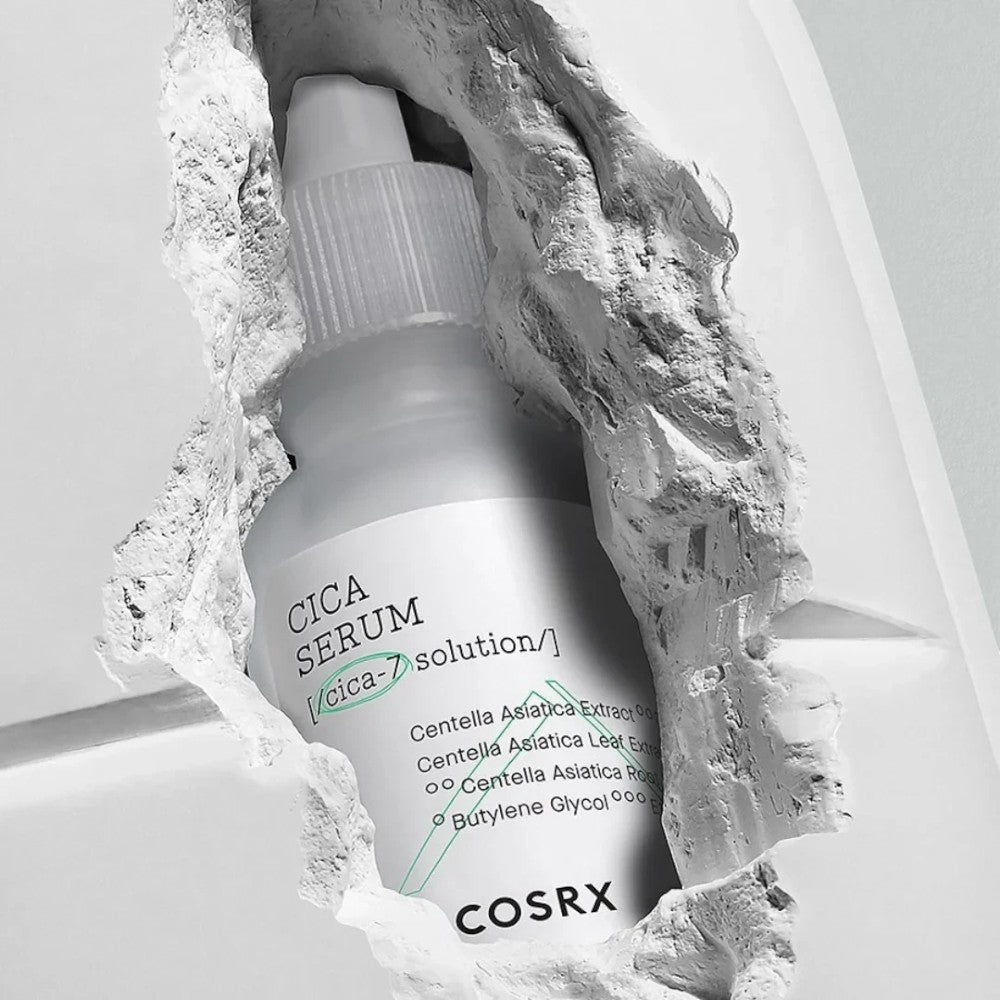 Skin TOGO COSRX Pure Fit Cica Serum in a 30ml bottle, displayed through a textured white stone opening.