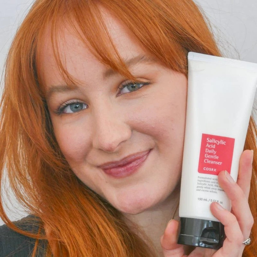 Skin TOGO model holding a white tube of Cosrx Salicylic Acid Daily Gentle Cleanser for acne-prone skin