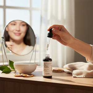 Skin TOGO Cosrx The Vitamin C 23 Serum bottle with dropper on a vanity table with a woman reflected in a mirror
