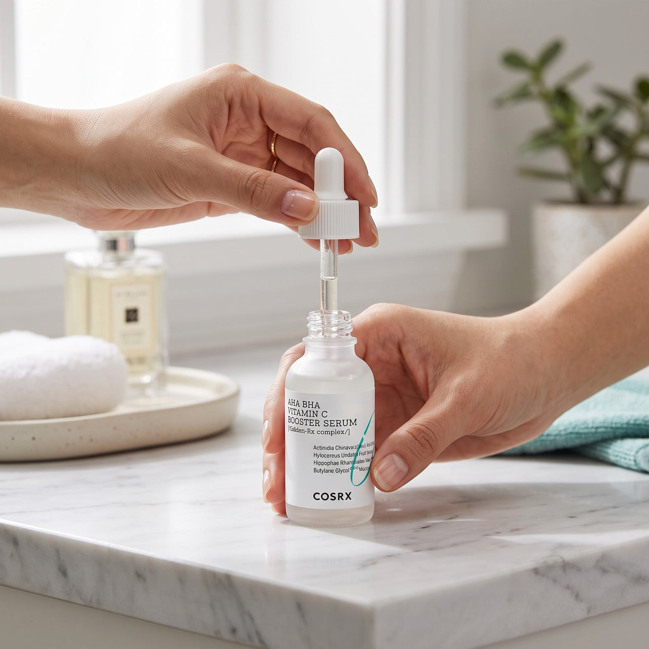 Skin TOGO COSRX AHA BHA Vitamin C Booster Serum in a white glass dropper bottle held by hands on a marble vanity.