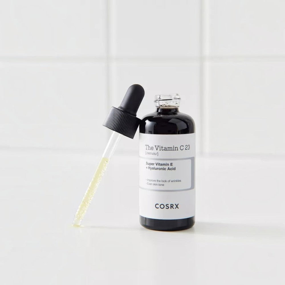 Skin TOGO Cosrx The Vitamin C 23 Serum in a dark glass bottle with a dropper on a white tiled background.