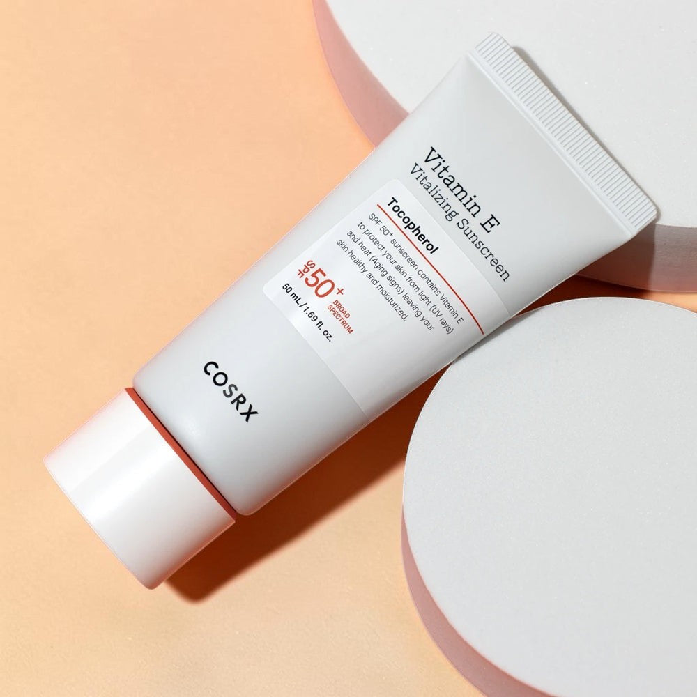 Skin TOGO COSRX Vitamin E Vitalizing Sunscreen SPF 50+ in a white 50ml tube on a peach and white platform