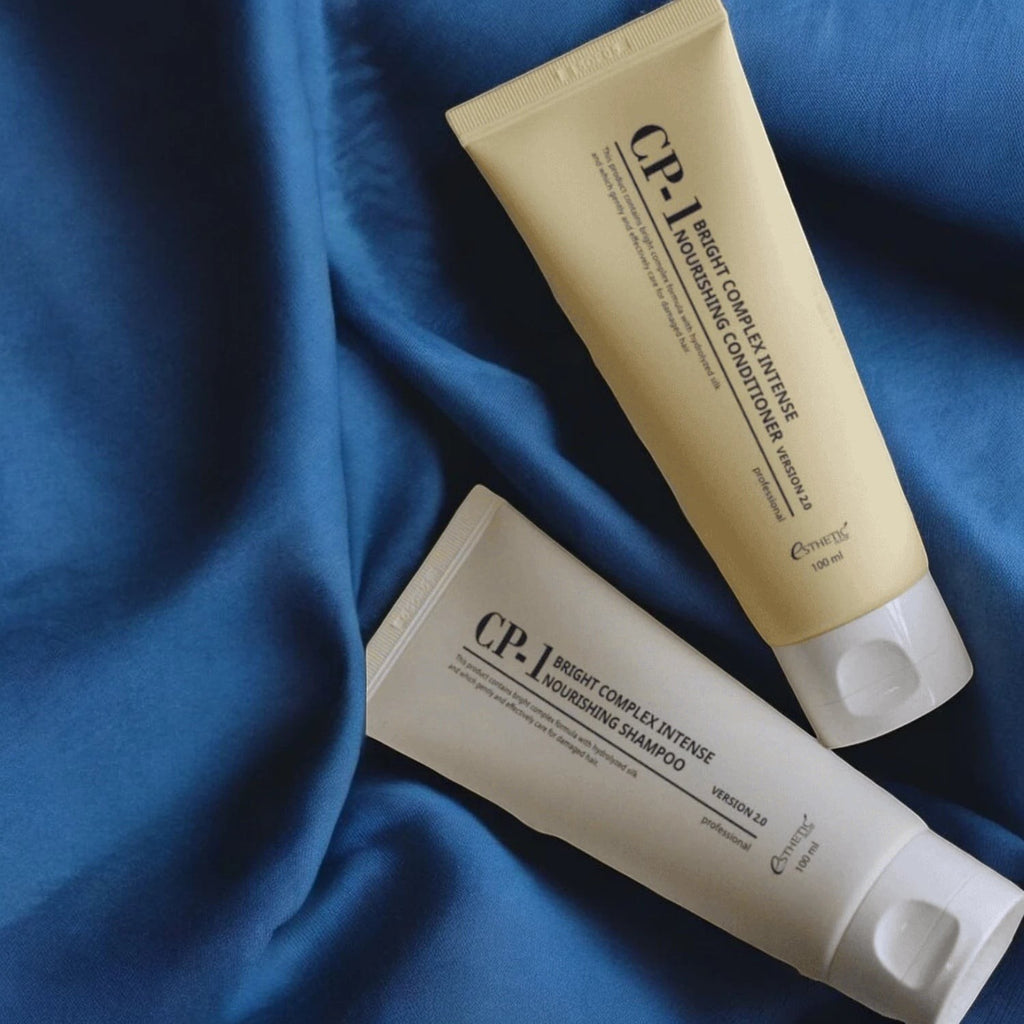 Skin TOGO CP-1 Bright Complex Intense Nourishing shampoo and conditioner tubes on blue fabric background
