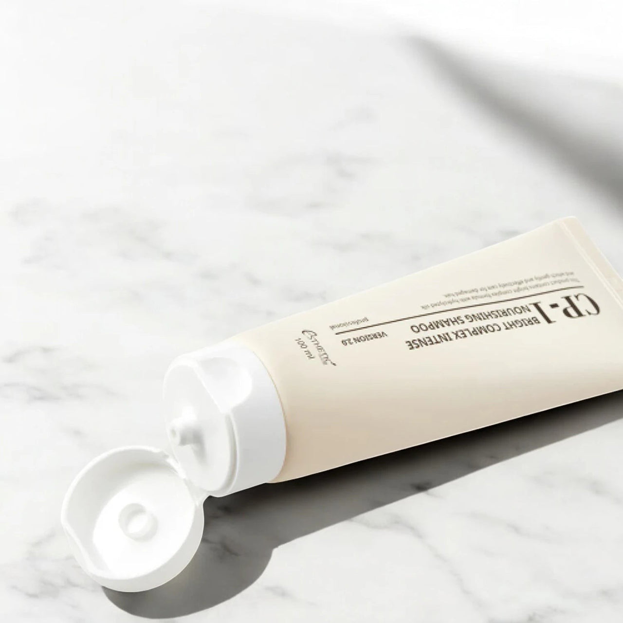 Skin TOGO CP-1 Bright Complex Intense Nourishing Shampoo 100ml tube on a white marble surface