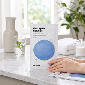 Skin TOGO Dr.Jart Vital Hydra Solution sheet mask on a marble counter with hands holding the hydrating skincare pack.