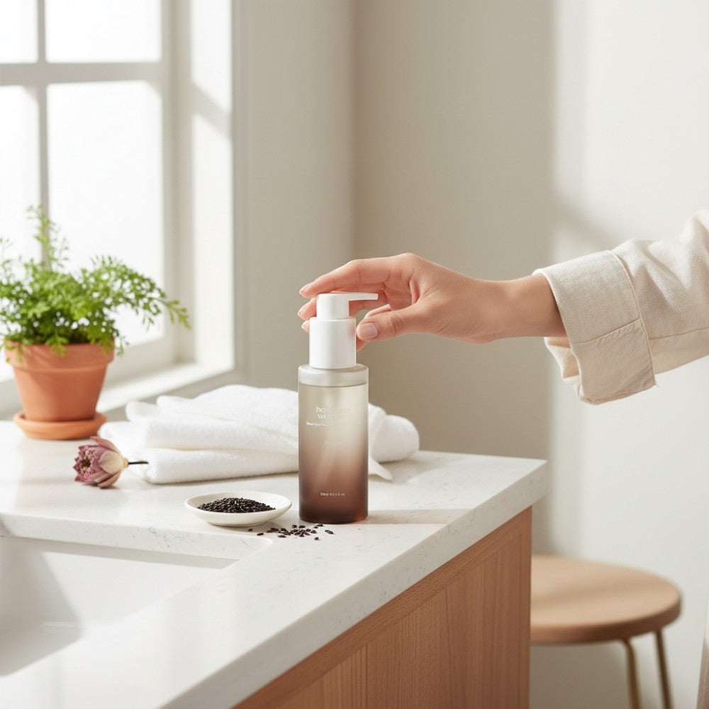 Skin TOGO Haruharu WONDER Black Rice Deep Cleansing Oil bottle on a bathroom counter with a hand pressing the pump.