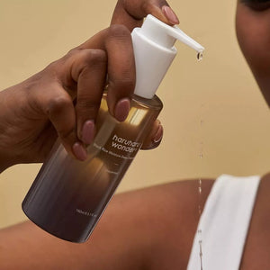 Skin TOGO Haruharu WONDER Black Rice Deep Cleansing Oil in a pump bottle being applied by a person with dark skin.
