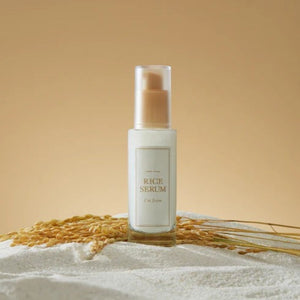Skin TOGO I'm from Rice Serum in a glass bottle with a pump, surrounded by rice grains on a beige background.