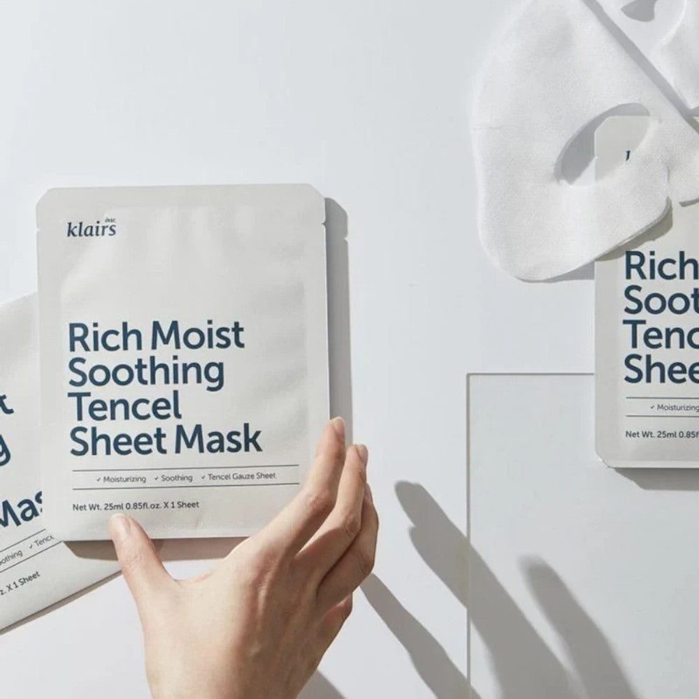Skin TOGO Dear, Klairs Rich Moist Soothing Tencel Sheet Mask packaging with a hand holding one of the masks.