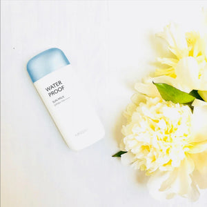 Skin TOGO MISSHA All Around Safe Block Waterproof Sun Milk bottle with SPF50+ PA++++ next to white peony flowers.