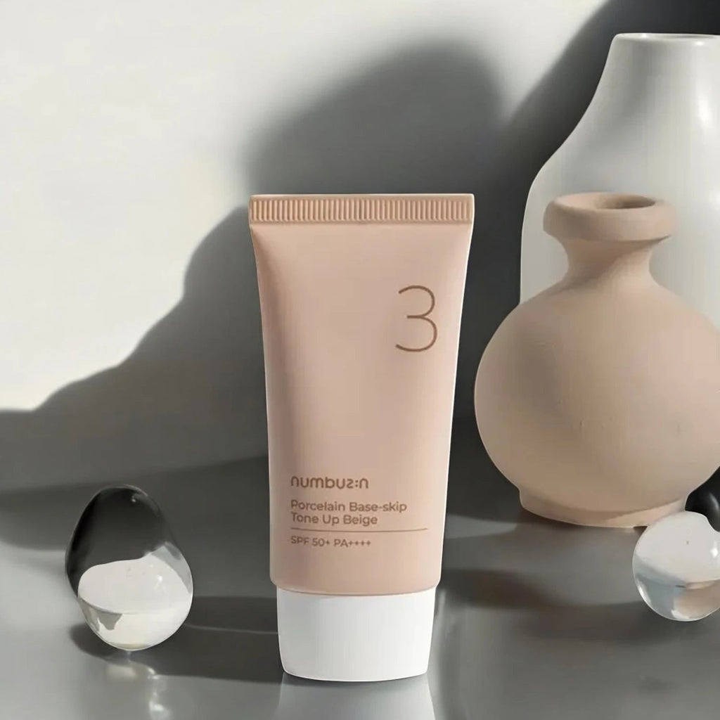 Skin TOGO Numbuzin No.3 Porcelain Base-Skip Tone Up Beige BB cream tube with SPF 50+ on a minimalist grey surface.