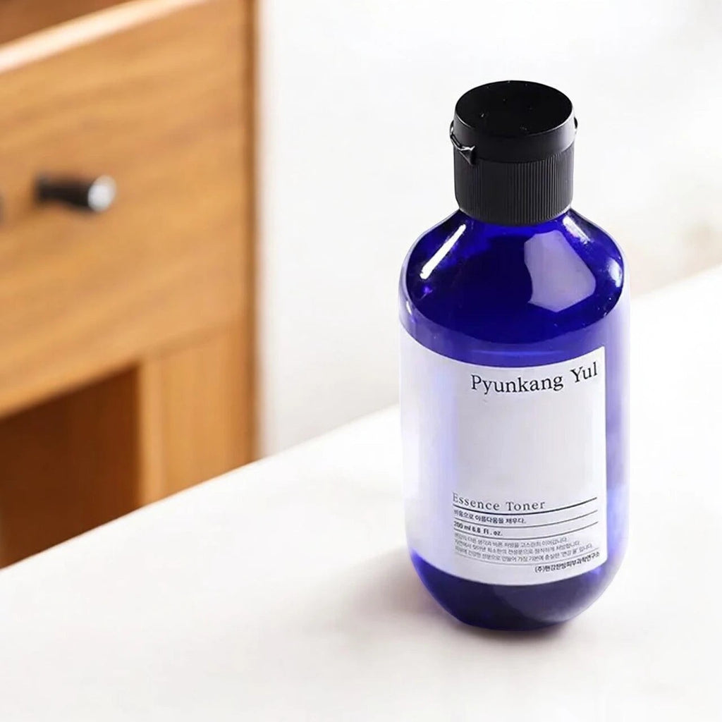 Skin TOGO Pyunkang Yul Essence Toner in a 100ml blue bottle with a minimalist white label on a white surface.
