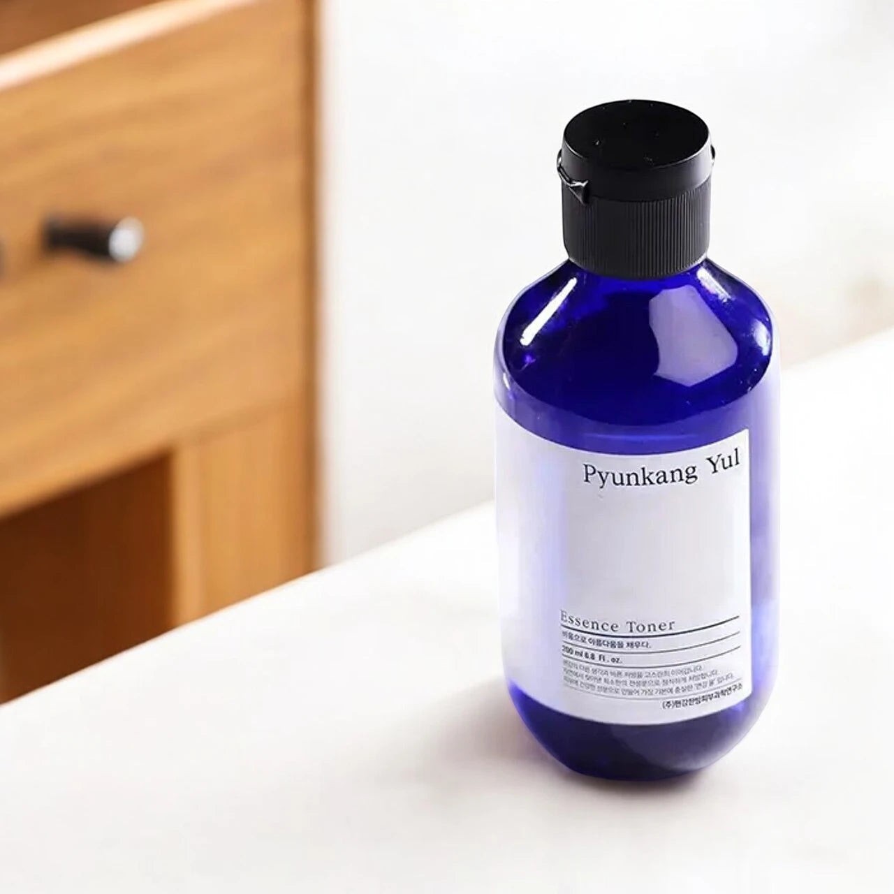 Skin TOGO Pyunkang Yul Essence Toner in a 100ml blue bottle with a minimalist white label on a white surface.