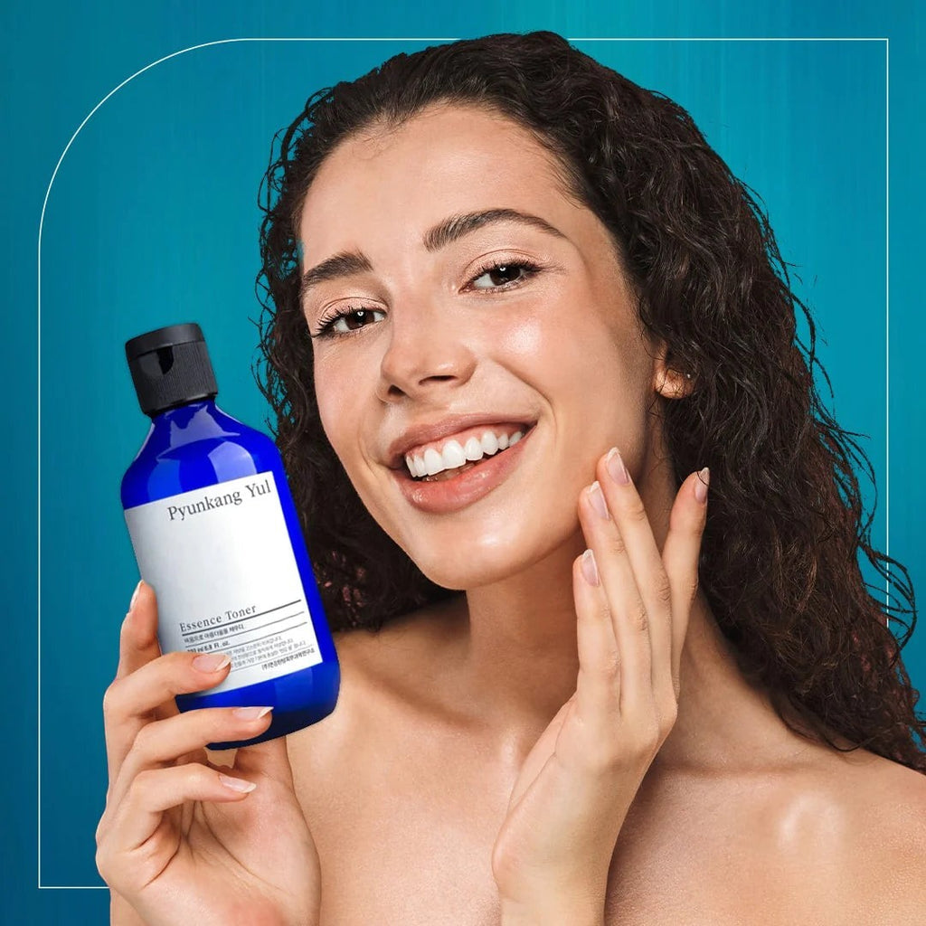 Skin TOGO model holding a 100ml bottle of Pyunkang Yul Essence Toner against a blue background