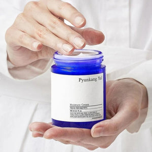 Skin TOGO Pyunkang Yul Moisture Cream in a blue glass jar held by hands, featuring a minimalist white label.