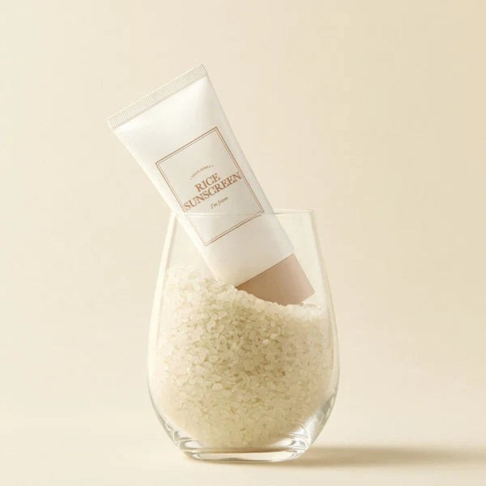 Skin TOGO I'm from Rice Sunscreen SPF50+ in a glass filled with white rice grains for a clean aesthetic.