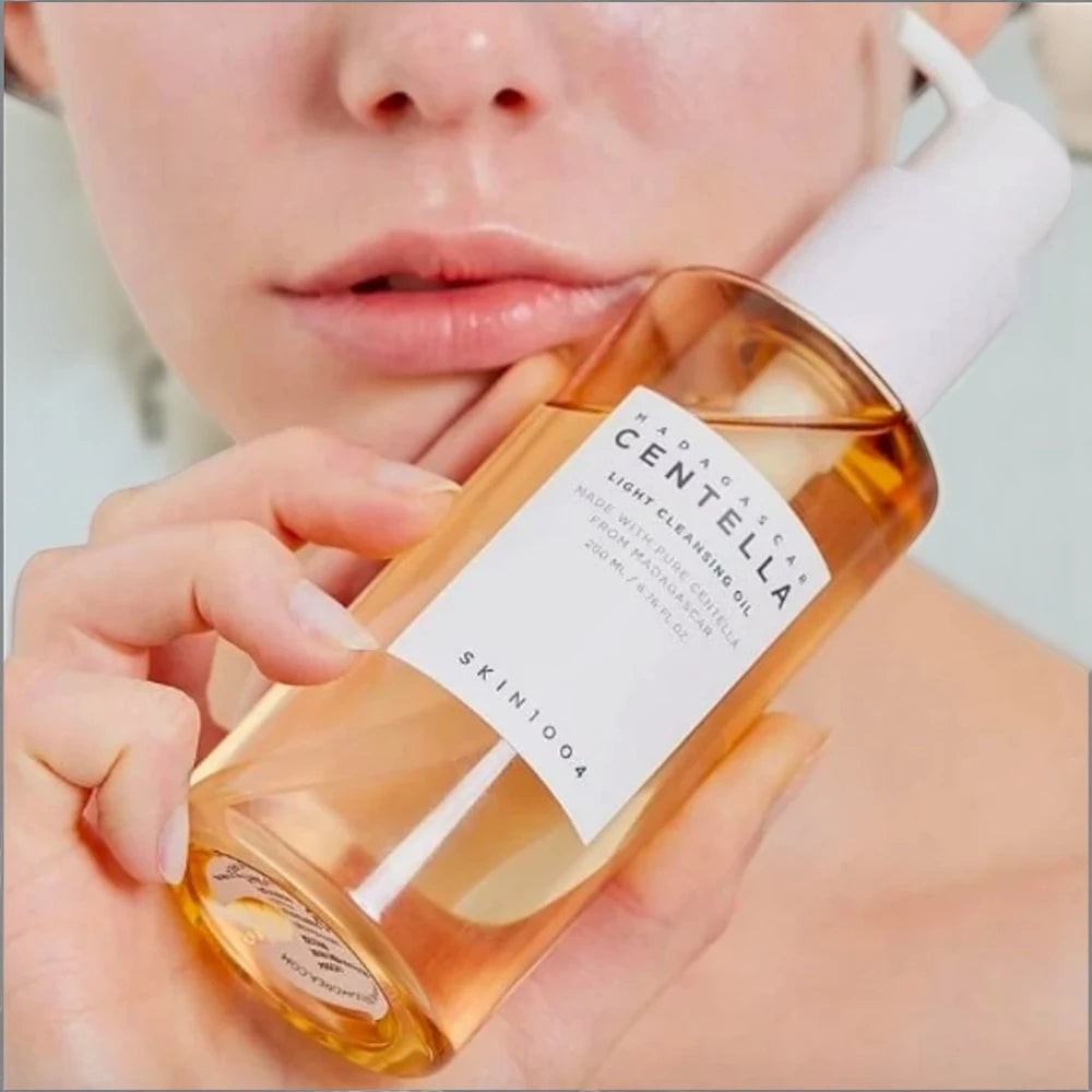 Skin TOGO model holding a 200ml bottle of SKIN1004 Madagascar Centella Light Cleansing Oil with a pump dispenser