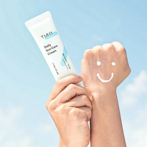 Skin TOGO TIAM Daily Sun Care Cream SPF50+ held in hand with a smiley face of sunscreen cream on the skin
