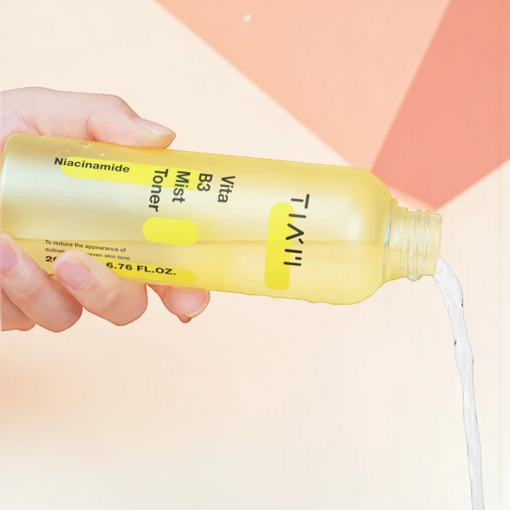 Skin TOGO TIAM Vita B3 Mist Toner being poured from a yellow spray bottle to show its lightweight liquid texture.
